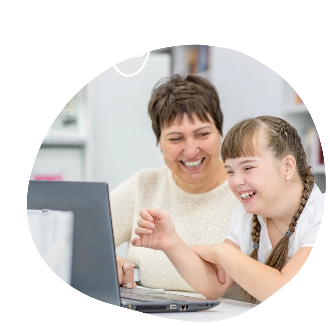 A disabled woman and her support worker laughing while looking at the laptop