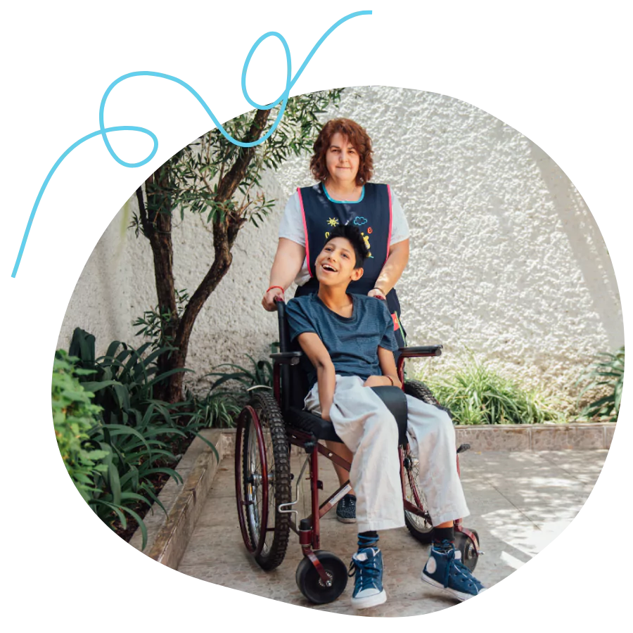 A disabled boy sitting in his wheelchair with his support worker