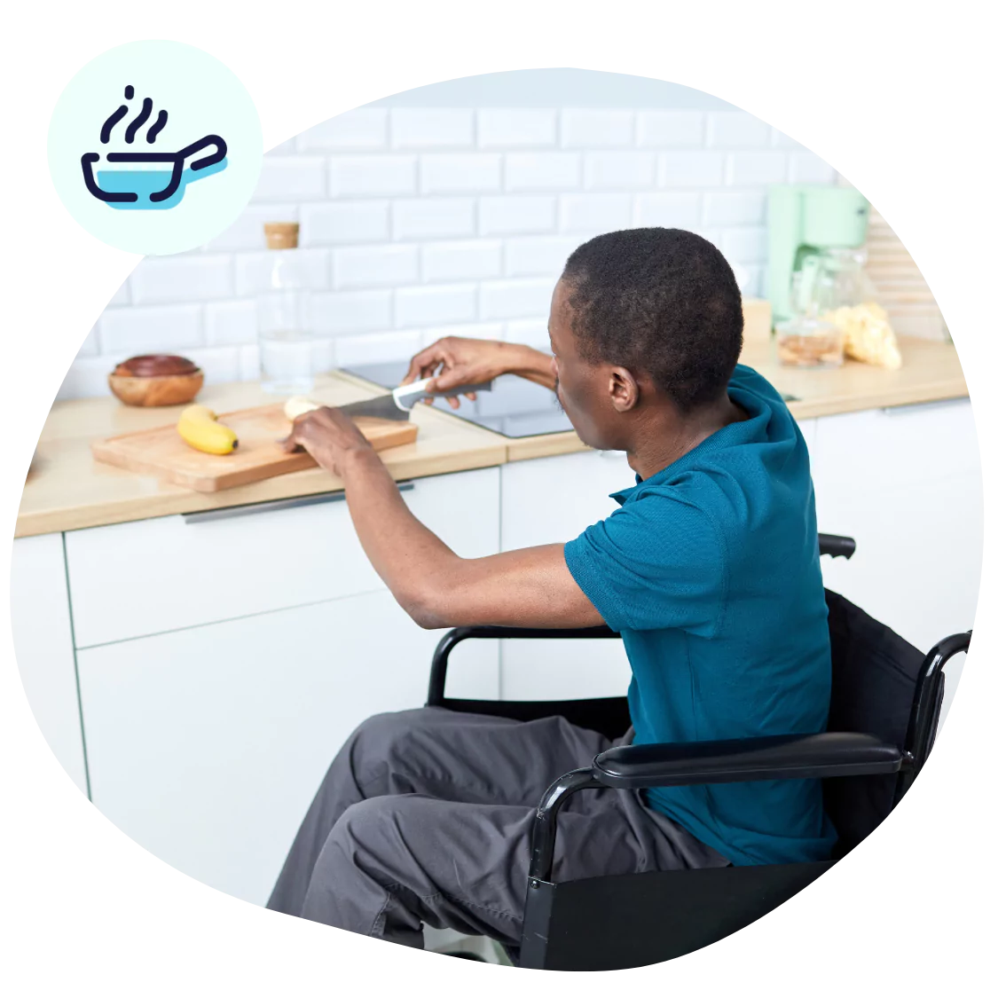 A disabled man sitting in his wheelchair cooking in the kitchen
